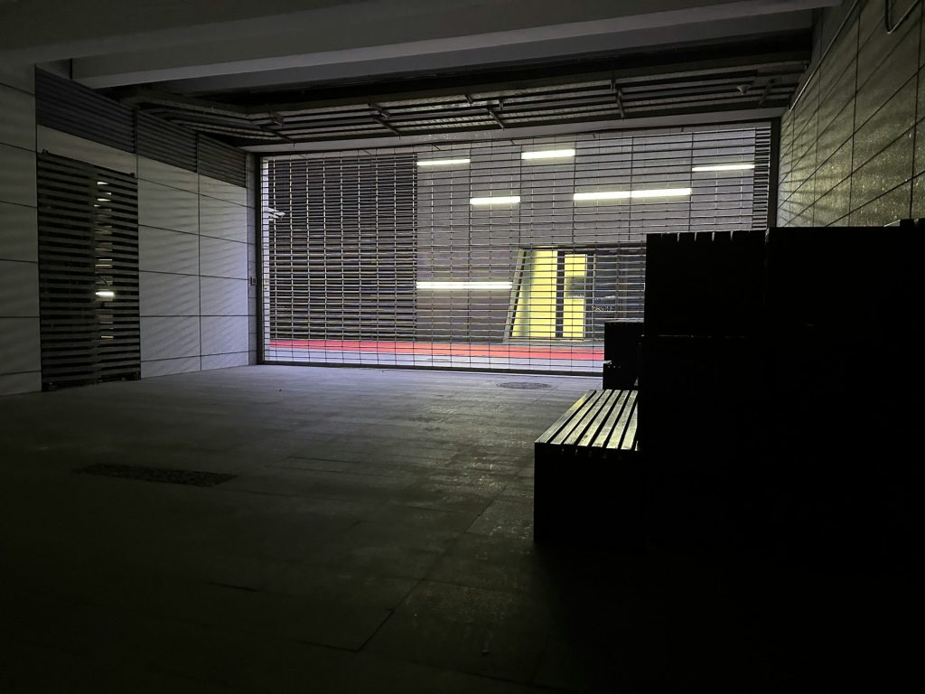 Un estacionamiento vacío con un banco delante.