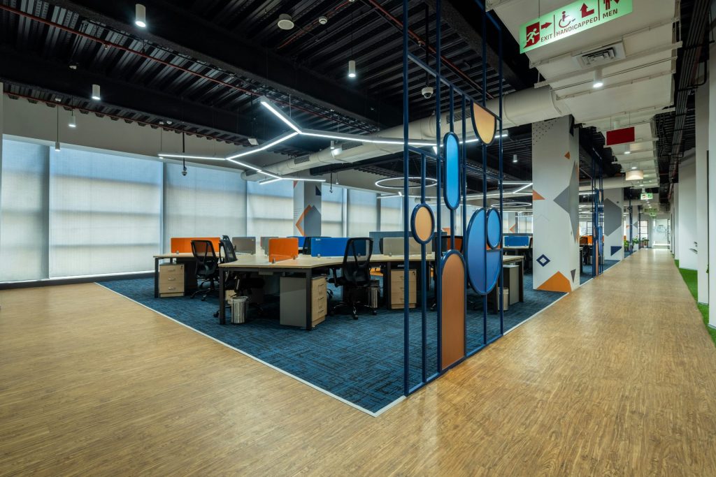 Una oficina con suelo de madera y sillas azules y naranjas.